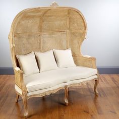 a wicker couch sitting on top of a hard wood floor next to a wall