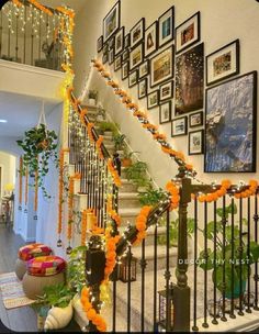 the staircase is decorated with orange garlands and pictures on the wall, along with potted plants