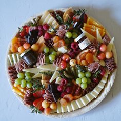 a platter filled with different types of cheeses and fruits on top of each other