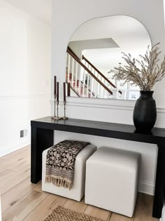 a black and white bench with two stools in front of it on a hard wood floor