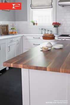 a cake sitting on top of a wooden counter in a kitchen next to white cabinets