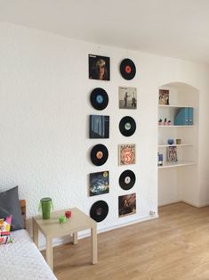 there are many records on the wall above the bed in this living room with wood flooring