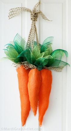 two carrots hanging on the front door with green leaves and burlocks attached to them