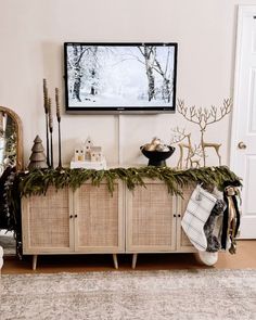 a living room with christmas decorations and a flat screen tv on the wall above it