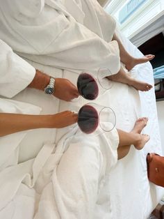 three people sitting on top of a bed with their feet propped up in the air