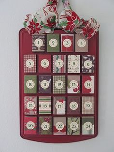 a christmas calendar hanging on the wall with red and white ribbons around it's edges