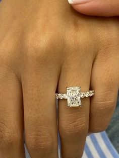 a woman's hand with a diamond ring on top of her finger and an engagement band