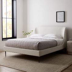 a white bed sitting next to a window in a bedroom on top of a rug