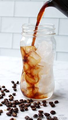 coffee being poured into a jar filled with ice and beans