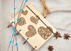 an intricate wooden notebook with hearts and arrows on the cover, surrounded by cinnamon stars