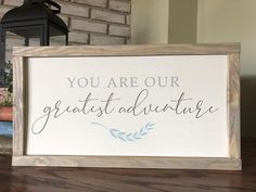 a wooden sign that says you are our greatest adventure on the table next to some books