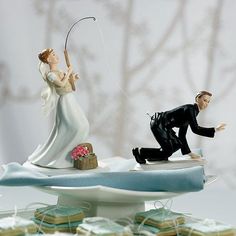 a wedding cake topper with a bride and groom fishing on the water, surrounded by cookies