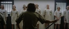 a man holding a baseball bat standing in front of a group of prison inmates