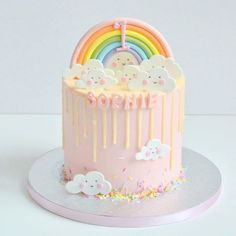 there is a pink cake with clouds and rainbows on it