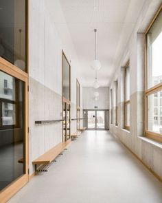 an empty hallway with multiple windows and wooden shelves on either side of the wall, leading to another room