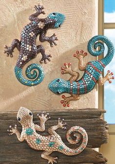 three geckos sitting on top of a piece of wood with blue and brown colors