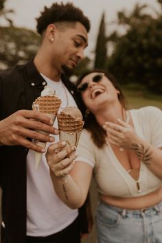 a man holding an ice cream cone next to a woman