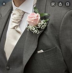 a man wearing a gray suit with a pink rose boutonniere on his lapel