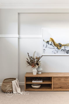 a vase with flowers on top of a wooden shelf in front of a white wall