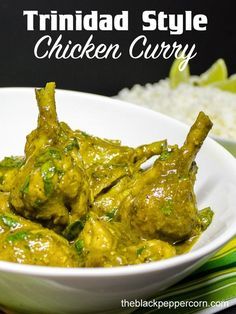 a white bowl filled with green curry next to rice and lime wedges on a table