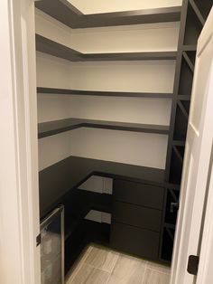 an empty closet with shelves and drawers in the corner is painted black, white and gray