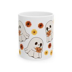 a white coffee mug with two ghost faces and sunflowers on the side,