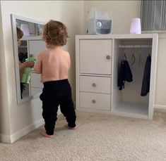 a small child standing in front of a mirror