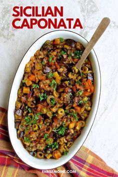 a white bowl filled with food sitting on top of a colorful table cloth next to a wooden spoon