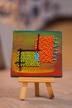 a small wooden easel sitting on top of a table with a painting on it