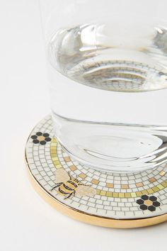 there is a glass on top of a coaster with a gold rim and flower designs