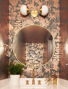 a bathroom sink with a round mirror and gold faucet on the wall above it