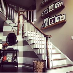 a staircase with pictures on the wall above it and a basket under the banister