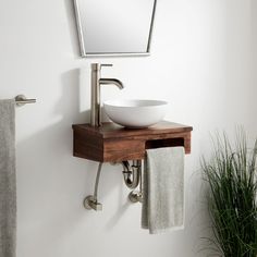 a bathroom sink sitting under a mirror next to a towel rack and potted plant