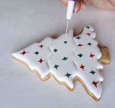 someone is decorating a cookie with icing and star designs on it to look like a christmas tree