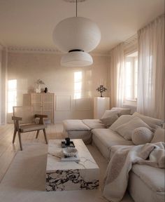 a living room filled with white furniture and lots of pillows on top of it's couches