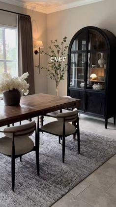 a dining room table with chairs and a vase filled with flowers on top of it