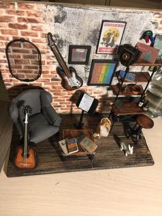 there is a miniature guitar and other items on the table next to it in front of a brick wall