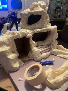 there is a fake cave made out of toilet paper and construction tape on the table