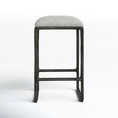 an upholstered stool sits on a plain white surface with no one around it