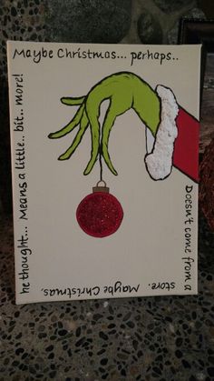 a hand holding a christmas ornament on top of a card