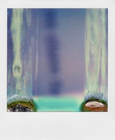 an abstract photograph of two poles in front of a blue and green background with white border