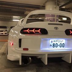 the back end of a white car in a parking garage