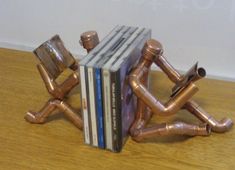 a stack of books sitting on top of a wooden table next to a metal pipe