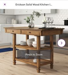 a kitchen island with plates and glasses on it in the middle of a wooden floor