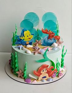 a birthday cake decorated with an ariel the mermaid scene and other disney princess characters on it