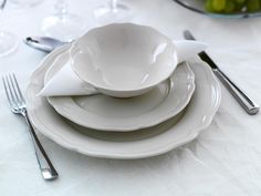 white plates and silverware are stacked on top of each other