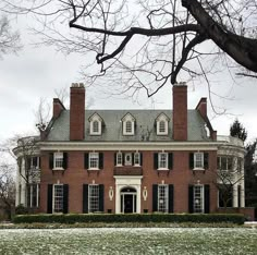 a large red brick house with black shutters on the front and side windows in winter