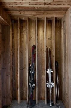 two skis are propped up in the corner of a room with wood paneling