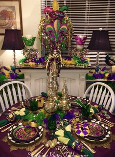 the table is set with plates, silverware and green decorations for mardi gras