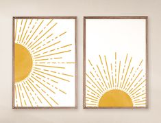 two yellow and white paintings on the wall in a living room, one with an abstract sun design